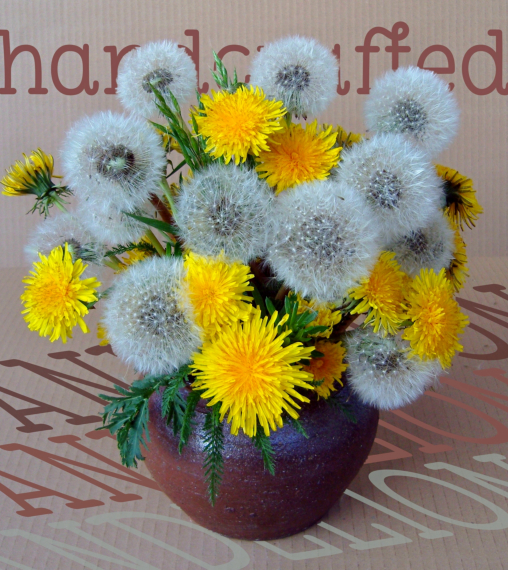Eine bachige Vase mit einem gemischten Strauß aus Löwenzahnblüten und Pusteblumen 